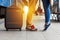 Legs Loving Couple happy hugging in the train station of a country after arrival with a warm sunlight background. Trolley broun ba