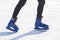 The legs of a man in blue skates rides on an ice rink