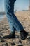 Legs of man in jeans and green socks on sand at a beach. Walking in comfortable shoes on beach.