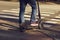 Legs of a man in jeans and sneakers on an electric scooter at a crosswalk on a city street