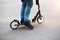 The legs of a man in jeans and sneakers on a scooter in the park on an asphalt track. Sports walk, healthy active lifestyle, eco-