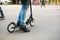 The legs of a man in jeans and sneakers on a scooter in the park on an asphalt track. Sports walk, healthy active lifestyle, eco-