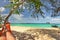 Legs of man laying in red hammock in tree shade