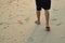 Legs of a man with slipper walking on the sand beach.
