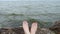 Legs and ocean. Concept video. Women legs on the background of the waves of the lake. The girl lies and enjoys the summer vacation