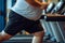 Legs of overweight person run on treadmill in gym