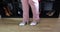 Legs in pink pants and female feet of standing adult woman trying on white, pink high heels and a bow