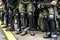 Legs of a policemen in protective ammunition and a green uniform. Knee pads, helmets, batons, boots