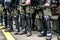 Legs of a policemen in protective ammunition and a green uniform. Knee pads, helmets, batons, boots