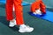 Legs in red pants and white sneakers on the rubber floor of the gym. A person engaged in gymnastics, using a soft mat for doing