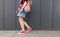 Legs in red sneakers, backpack and denim dresses go down the ground against the background of a dark wall