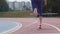 Legs in red snikers of a young woman athlete who starts running at the city athletics track during training in slow