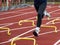 Legs of a runner running over six inch yellow hurdles on a track