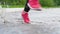 Legs of a runner in sneakers. Sports woman jogging outdoors, stepping into muddy puddle. Single runner running in rain