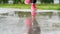 Legs of a runner in sneakers. Sports woman jogging outdoors, stepping into muddy puddle. Single runner running in rain