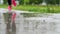 Legs of a runner in sneakers. Sports woman jogging outdoors, stepping into muddy puddle. Single runner running in rain