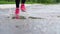 Legs of a runner in sneakers. Sports woman jogging outdoors, stepping into muddy puddle. Single runner running in rain