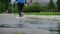 Legs of a runner in sneakers. Sports woman jogging outdoors, stepping into muddy puddle. Single runner running in rain