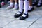 Legs of schoolgirls in different shoes on the sidewalk