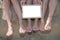 Legs of several girls on sand beach with white blank empty billboard foir message advertising