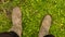 The legs are shod in old boots. Farmer`s feet in boots standing on green grass