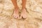 Legs slender seven-year girl standing barefoot on the sand