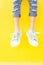 Legs sneakers on yellow background, lifestyle fashion