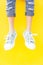 Legs sneakers on yellow background, lifestyle fashion