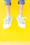 Legs sneakers on yellow background, lifestyle fashion