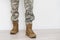 Legs of a soldier in camouflage and army boots on a gray background. Military conflicts and crises. Close-up