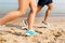 Legs of sportsmen in sneakers running along beach