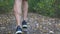 Legs of sporty man running along trail in early autumn forest. Male feet of young athlete sprinting fast along path at