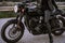 Legs of stylish motorcyclist woman sitting on classic bike. Black retro-styled motorcycle. Details of vintage design of