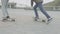 Legs of teen friends skateboarding on city square