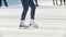 Legs of a teen girl skillfully skating on outdoor public ice rink, slow-motion