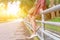 Legs of teenage asian girl sitting alone on fence on summer day.