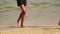 Legs of two young ladies spend summer vacation time strolling on white sandy beach