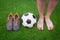 Legs of unrecognizable barefoot football player, soccer ball and sport shoes against artificial grass.