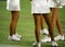 Legs of unrecognizable cheerleaders standing in a football field sideline