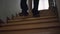 Legs of unrecognizable stylish man in suit and leather shoes walking downstairs at home. Young wealthy confident guy