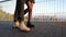 Legs of unrecognizable young couple walking on bridge at summertime. Sunset light. Stylish happy pair in business