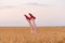 Legs upwards against the sky and fields of ripe wheat. Feet in red shoes sticking out from field