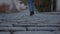 Legs of a woman in black boots and jeans walking along cobbled streets of European cities in close up