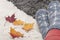 Legs of woman in knitted socks with snowflakes and colorful autumn leaves