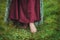 Legs of woman in long medieval dress walking in summer field