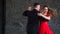 Legs of woman in red and man in black dancing tango near window. Close-up of dansers Legs.