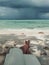 Legs of a woman resting with notepad on a sunbed by the ocean. Maldivian white sand beach.