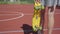 Legs of woman in short skirt with a yellow skateboard walking on the basketball court. Shadow follows the girl. Concept