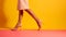 Legs of woman in stiletto high heel shoes on colored background