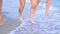 Legs womens tanned runing on sandy beach on sunset. Slim pretty girls go by the sea on golden sand. Friends on vacation.